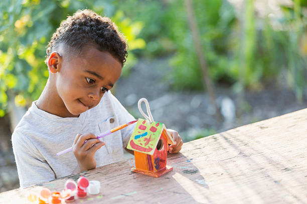 Little boy painting bird house Little boy (5 years) painting bird house. nesting box stock pictures, royalty-free photos & images