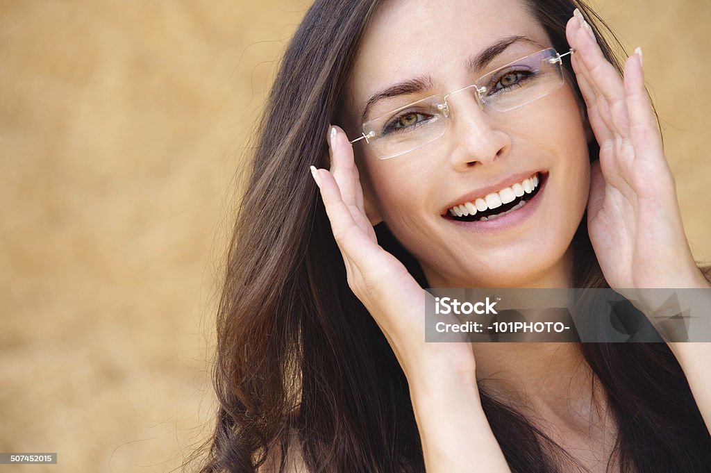 young laughing woman wearing eyeglasses Close-up portrait of young beautiful brunette woman wearing glasses against beige background. Awe Stock Photo