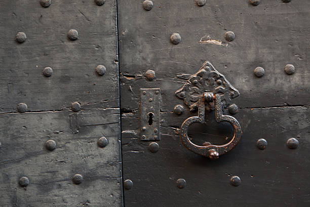 istock Old metal doorknocker on the black painted wooden gate 507453148