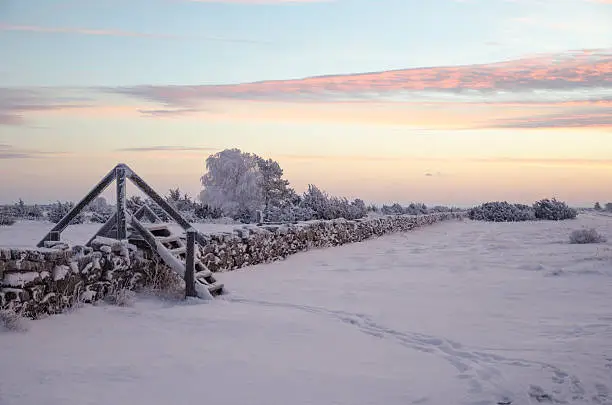 Photo of Dawn at a winterland with a stile by stone wall