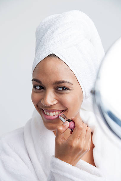 istock African female putting on lipstick looking into the mirror. 507455987