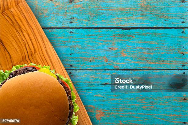 Dressed Burger On Blue Picnic Table Stock Photo - Download Image Now - Beef, Bun - Bread, Burger