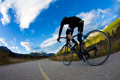 A male road cyclist rides a designated bike path in the Rocky Mountains of Canada in the fall.