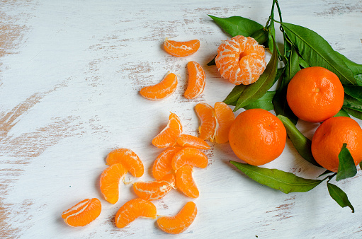 Ripe tangerines and tangerine slices on a white painted boardRipe tangerines and tangerine slices on a white painted board