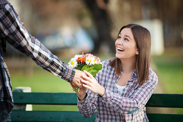 Young valentines on a date Young woman receiving a bunch of wild flowers on a date chivalry stock pictures, royalty-free photos & images