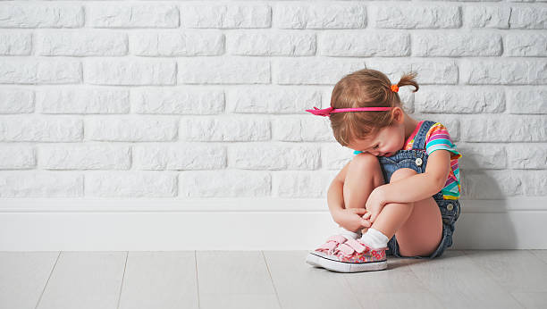 piccolo bambino ragazza triste pianto e muro di mattoni - child sadness little girls thinking foto e immagini stock