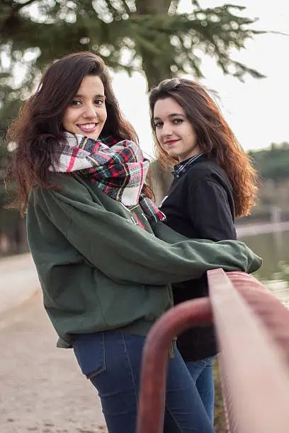 Photo of Two girls leaning of a railing watching the lake.