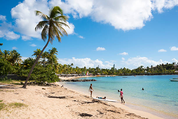 Morris Bay, Antigua and Barbuda - November 15, 2015: Children swim at the beach in Morris Bay on the island of Antigua. In the background is Curtain Bluff Resort.