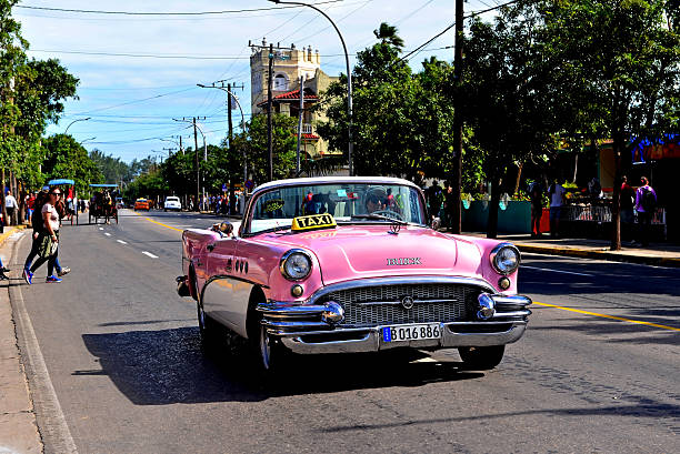 Varadero, Cuba - January 18, 2016:  Taxi Driver drives his vintage Buick down the main street in Varadero.  Cuba has many vintage cars and horse drawn carriages being used as taxis.