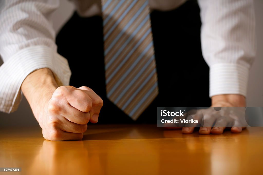 Businessman hitting table with clenched fist. A DSLR photo of a businessman hitting the table with clenched fist. Can illustrate the concept of stress, disagreemnet, anger, etc. Arguing Stock Photo