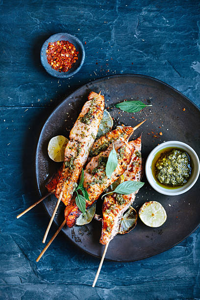Salmon satay Salmon satay with pesto and chili sauce and herbs mediterranean food photos stock pictures, royalty-free photos & images