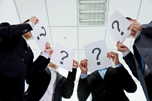 Business team holding question mark signs in office.