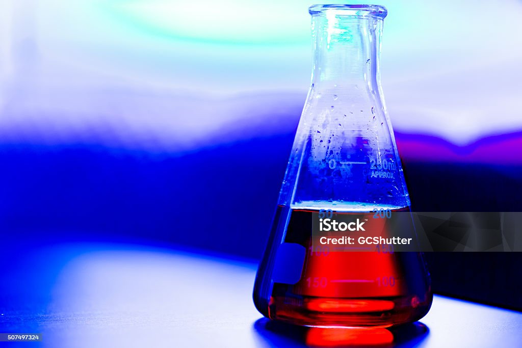 Flask containing chemical in a lab View from a science lab, flask containing red chemical stored on a desk. Analyzing Stock Photo