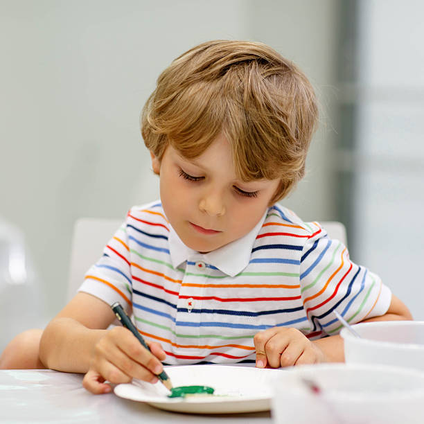 istock Little blond boy mixing different colors and painting 507498134