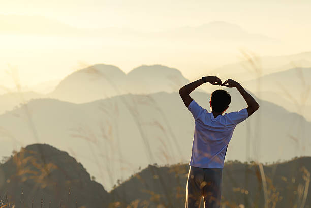 istock Man forming heart shape at sunset with heart shaped mountains. 507499670