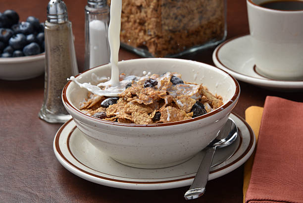 Pouring milk onto cereal Pouring milk onto a bowl of bran flakes with raisins.  High speed freeze motion photography bran flakes stock pictures, royalty-free photos & images