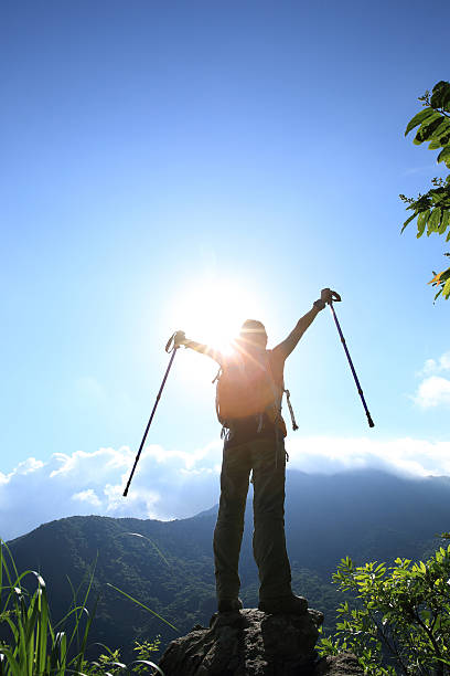 istock cheering young woman hiker open arms at mountain peak 507512246