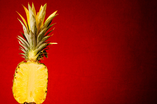 A pineapple cut in half against a warm red background