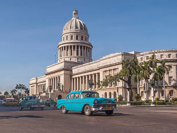 old American cars passing in front of the Capitolio in Havana, Cuba