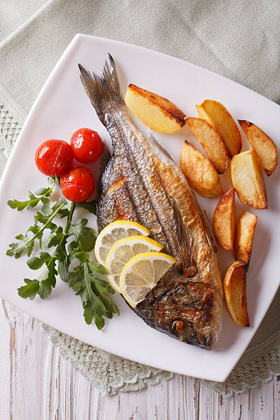 istock Grilled dorado fish with fried potatoes close-up. Vertical top v 507514704