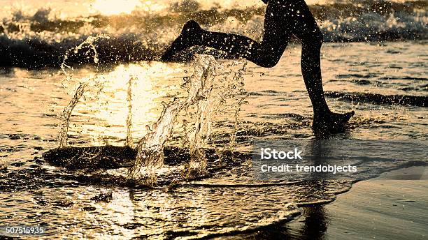 By The Sea Running On The Beach At Sunset Stock Photo - Download Image Now - Barefoot, Beines, Breaking Wave