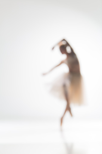 Blurred silhouette of ballerina dancing on white background
