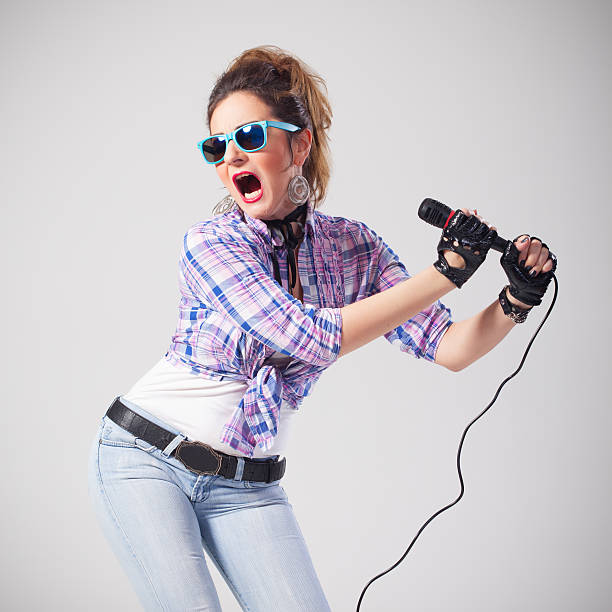 istock Funny woman with sunglasses singing loud on microphone 507518400