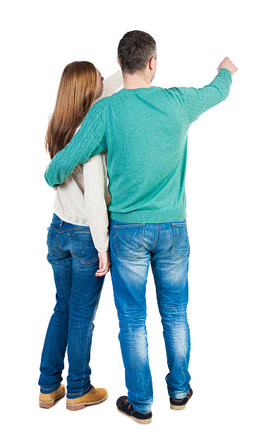young couple pointing at wal Back view young couple pointing at wal Back view  (woman and man). Rear view people collection.  backside view of person.  Isolated over white background. Man and woman embracing each other to point the finger somewhere to the right. man touching womans buttock stock pictures, royalty-free photos & images