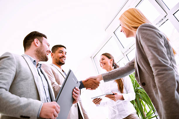 Business Agreement Handshake between two business executives.Image of four successful business partners working at meeting in office.They are working on a new project. business relationship stock pictures, royalty-free photos & images