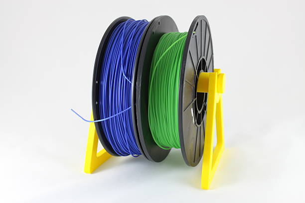3D printing filament reels on distribution spool Blue and green 3D printing filament reels on yellow distribution spool 3d printing filament photos stock pictures, royalty-free photos & images