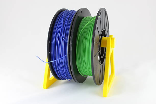 3D printing filament reels on distribution spool Blue and green 3D printing filament reels on yellow distribution spool polylactic acid stock pictures, royalty-free photos & images