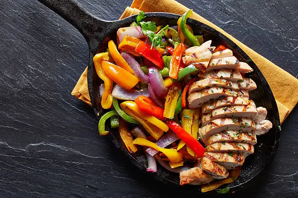 Photo of mexican grilled chicken fajitas in iron skillet