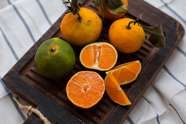 fresh tangerines with leaves on wooden cutting board stock photo