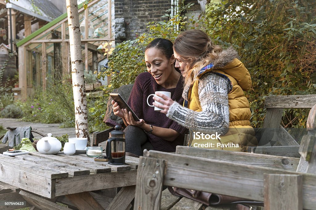Mujeres jóvenes disfrutar de un té de media tarde, Urban la ciudad, el jardín, London - Foto de stock de Grupo multiétnico libre de derechos