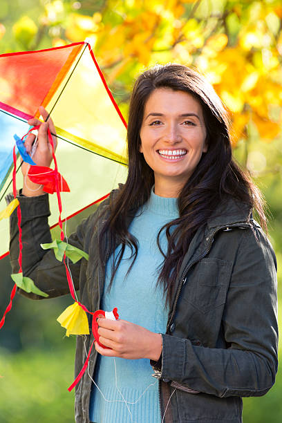 Young woman outdoors in autumn, flying kite.