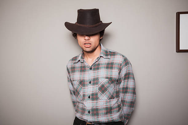 istock Young cowboy in plaid shirt against a green wall 507546449