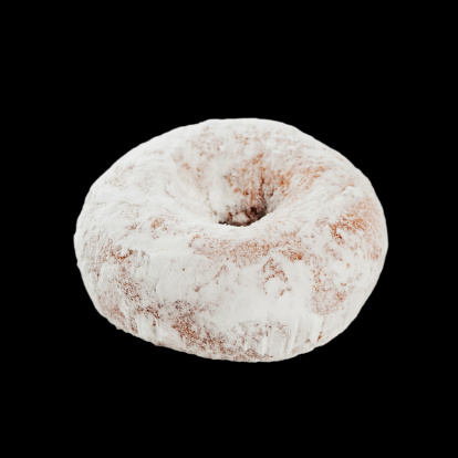 A mini sugar donut isolated on a black background.