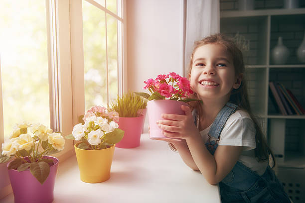 dziewczyna stawia kwiaty - roślina pokój dziecinny zdjęcia i obrazy z banku zdjęć