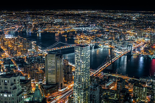 Aerial view of Brooklyn and Manhattan bridges with wide surrounding areas around them on a cold winter night.