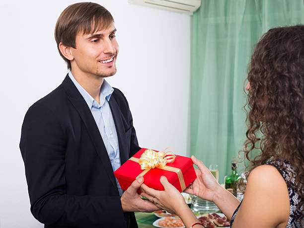 Smiling  man giving present to beautiful woman Smiling  man giving present to beautiful woman during romantic dinner in home wonderingly stock pictures, royalty-free photos & images