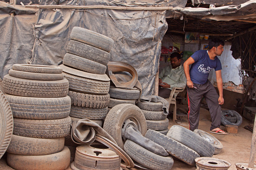 Madhya Pradesh, India – February 28, 2015: Unidentified worker at a tire replacement service at a rural truck stop. The vast number of motor vehicles on Indian roads means an abundance of such small businesses at roadsides throughout the country
