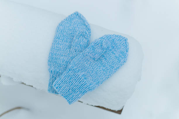 istock Mittens in snow. Blue knitted gloves in winter 507569222