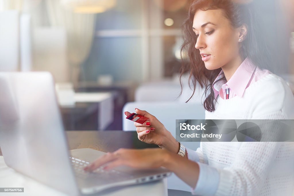 Young businesswoman drinking coffee and using laptop computer in cafe Young businesswoman drinking coffee and using laptop computer in cafe doing online shopping, holding credit card Credit Card Stock Photo