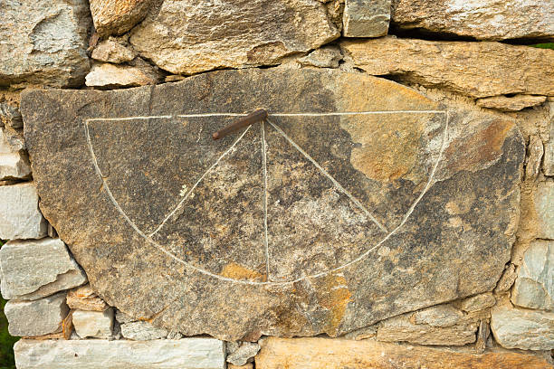 Old sundial painted on a stone wall of the romanesque church tower dating from the 13th century in Obersaxen, Switzerland.