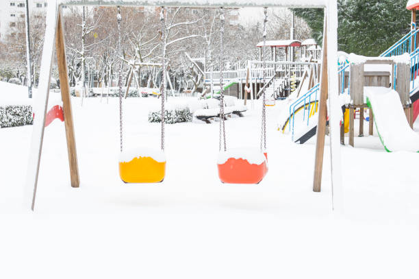 snow covered swing and slide at playground in winter