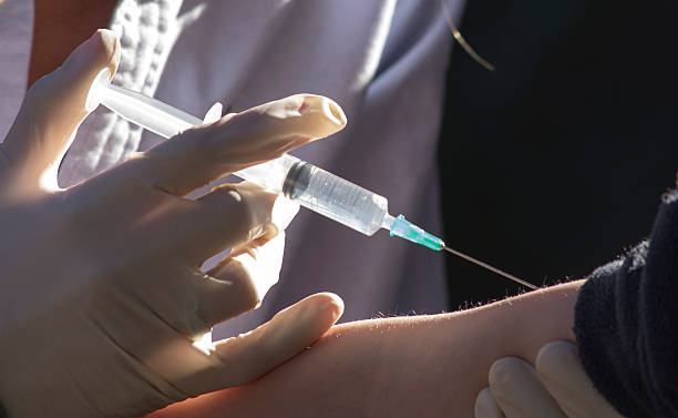 Injection Giving an injection to a child in his arm. pox stock pictures, royalty-free photos & images