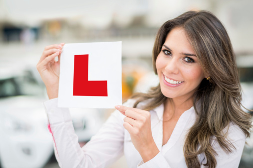 Woman holding a learning sign for the car