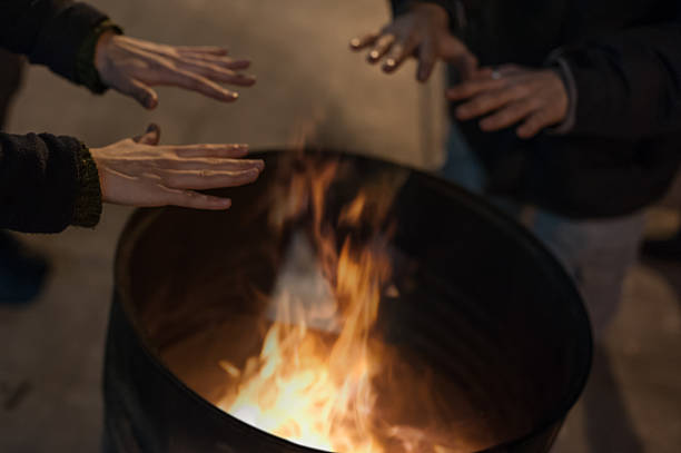 istock Homeless man warming his hands by a fire 507580440