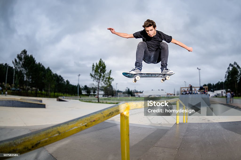 Skateboarder doing a ollie Skateboarder doing a ollie over the rail at the skate park. Skateboarding Stock Photo