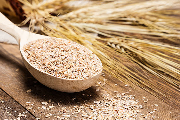 gros plan de cuillère en bois avec de blé bran - bran flakes photos et images de collection